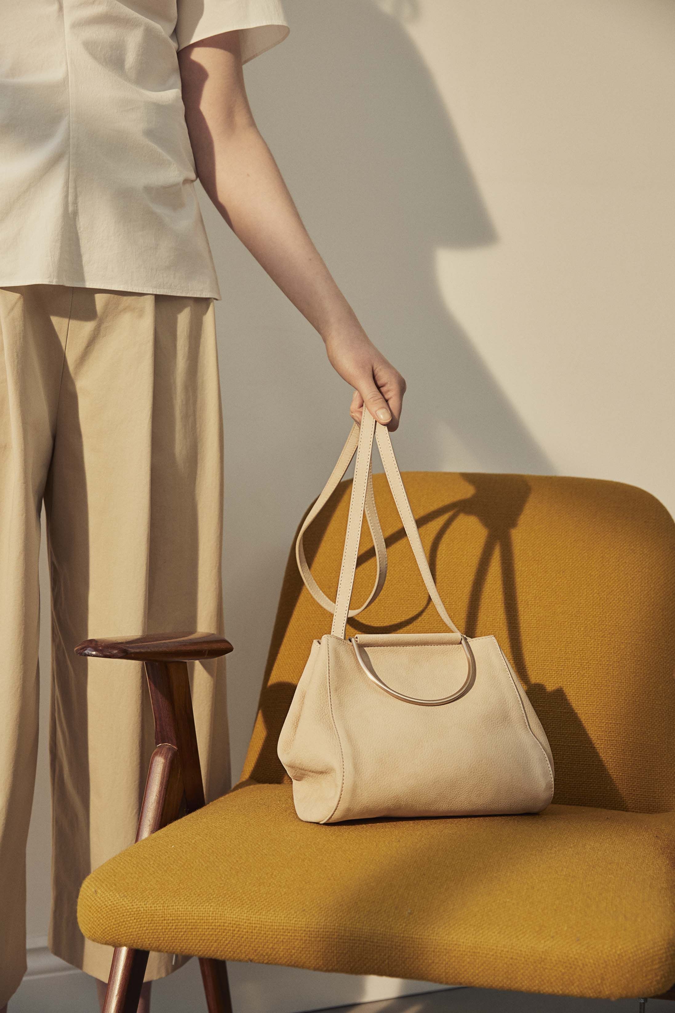 Model holding an elegant cream handbag